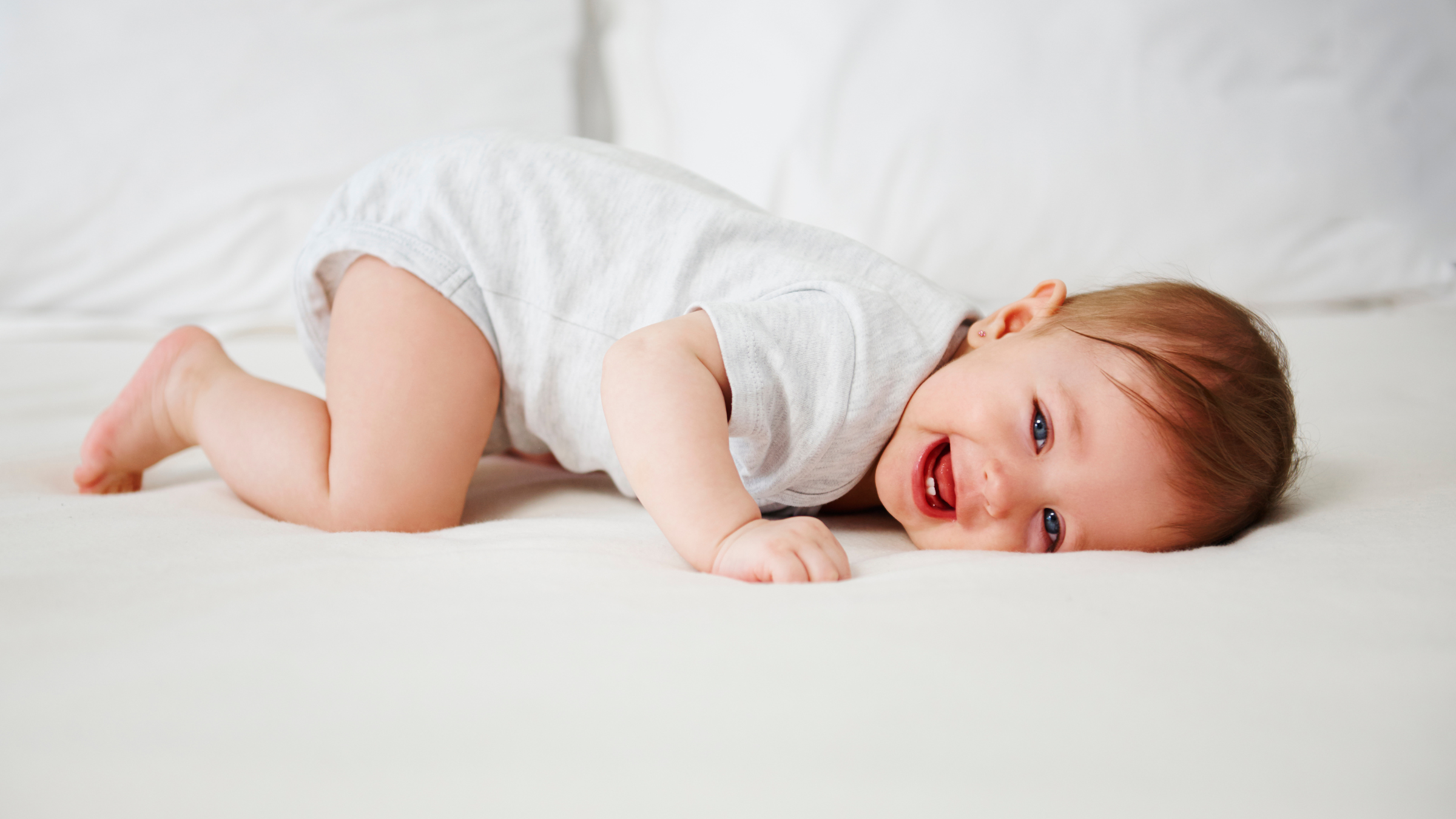 Baby lying on a white blanket with a white background